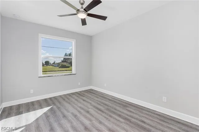 an empty room with a window and ceiling fan
