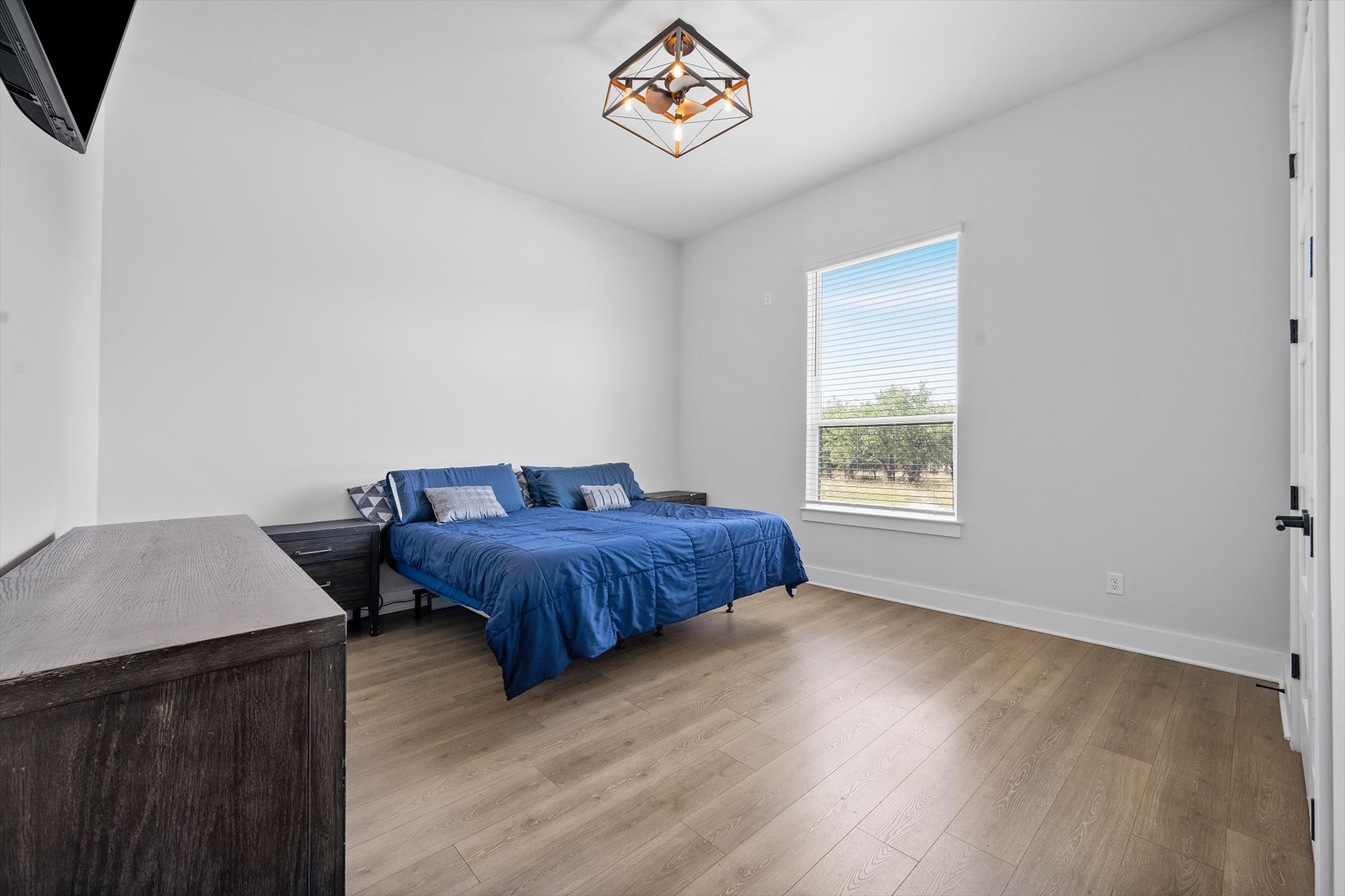 638 Strada Luca Florence, TX 76527 - Photo 19 of 38 Laminate wood flooring grounds this naturally illuminated bedroom with a modern light fixture.
