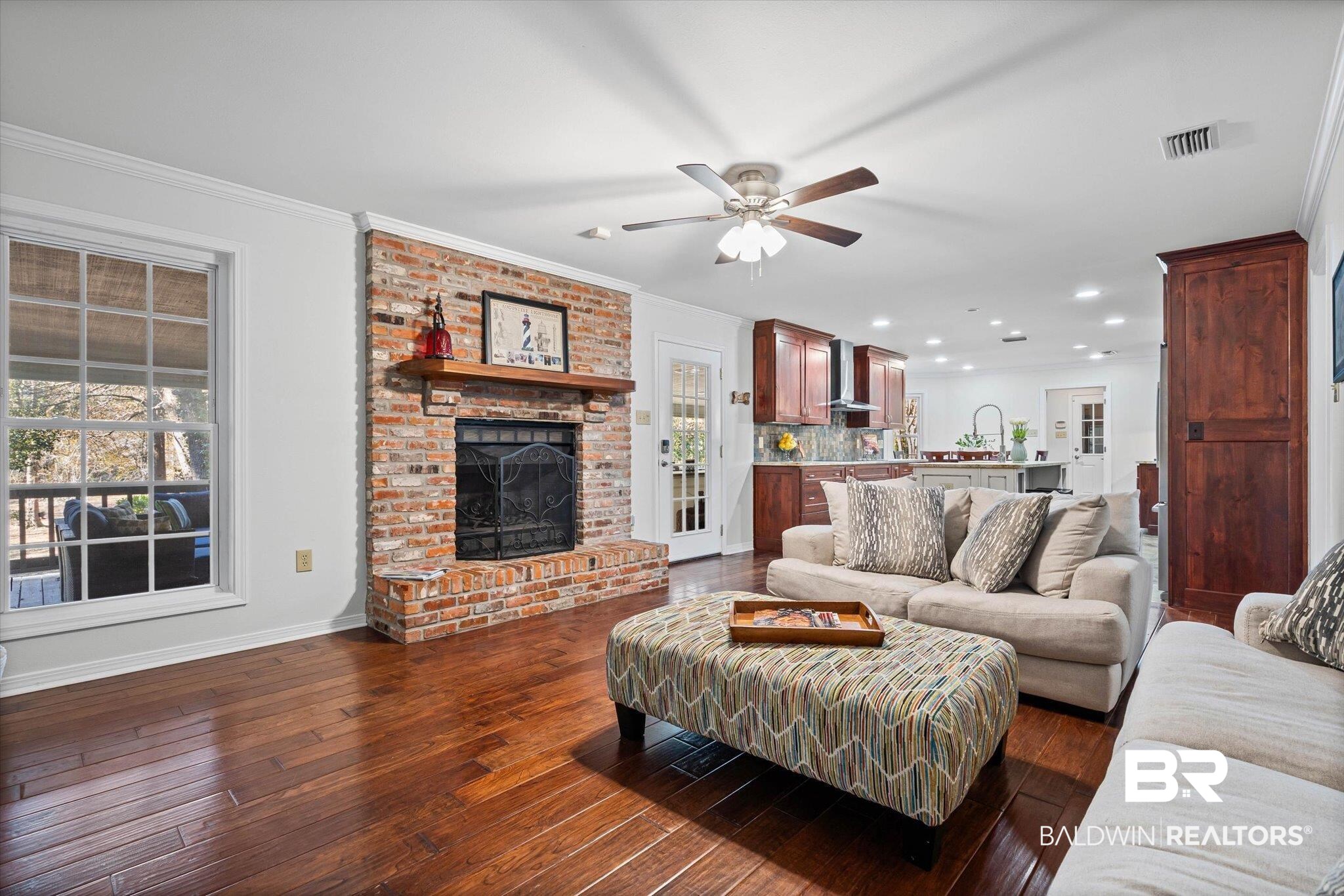 31369 Blakeley Way Daphne, AL 36527 - Photo 5 of 38 Living area featuring a fireplace, dark wood-style flooring, ornamental molding, a ceiling fan, and plenty of natural light
