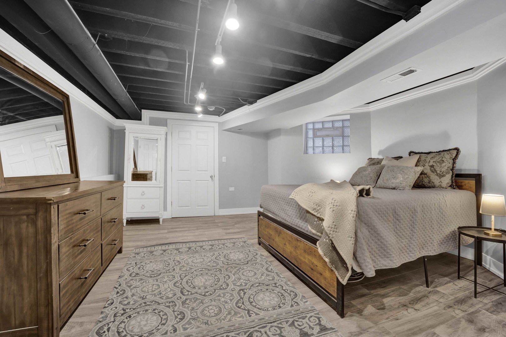 3806 South Indiana Avenue Chicago, IL 60653 - Photo 29 of 35 a spacious bedroom with a bed a mirror on dresser and a wooden floor