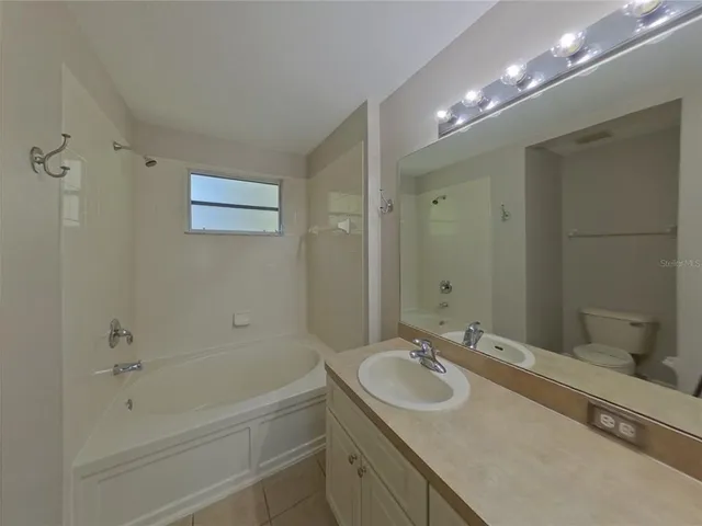 a bathroom with a granite countertop sink mirror and a bathtub