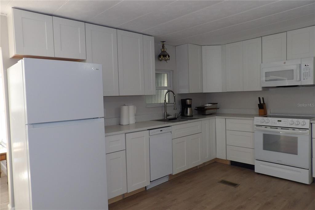 6608 Roosevelt Drive Port Richey, FL 34668 - Photo 16 of 39 a kitchen with white cabinets and white appliances
