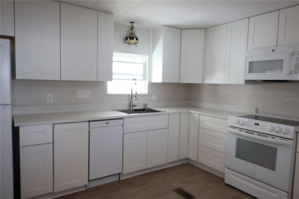 6608 Roosevelt Drive Port Richey, FL 34668 - Photo 17 of 39 a kitchen with white cabinets and white appliances