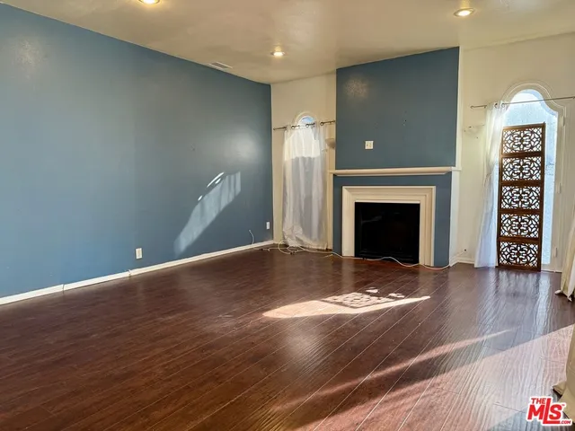 a view of empty room with wooden floor and fireplace