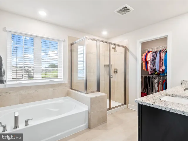a bathroom with a granite countertop tub a sink and a shower