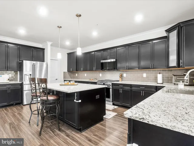 a kitchen with kitchen island granite countertop a sink stove and refrigerator