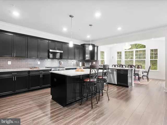 a kitchen with stainless steel appliances granite countertop wooden cabinets a sink dishwasher a stove and a refrigerator with wooden floor