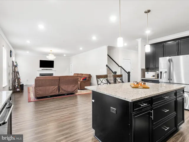 a large kitchen with stainless steel appliances granite countertop a lot of counter space and a wooden floor