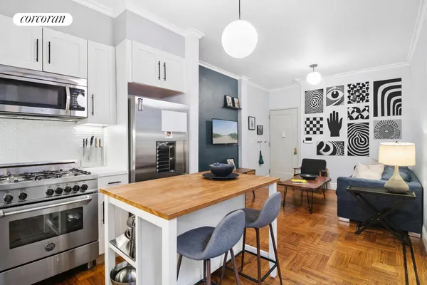a kitchen with stainless steel appliances a stove a sink dishwasher a dining table and chairs with wooden floor