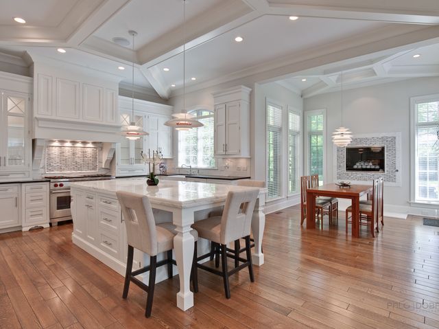 a kitchen with stainless steel appliances granite countertop a stove a refrigerator a kitchen island with a dining table and chairs