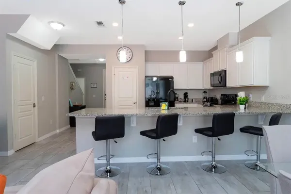 a kitchen with stainless steel appliances kitchen island granite countertop a refrigerator a stove a kitchen island a couches and chairs