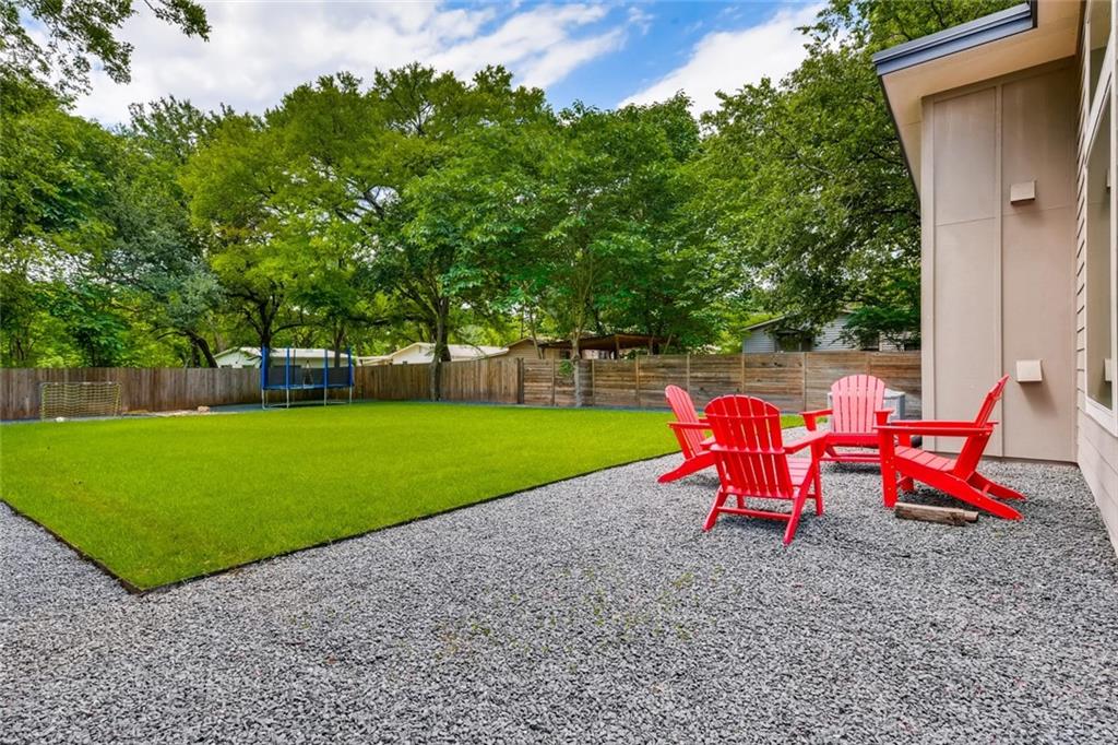 1142 Eleanor Street, Unit 2 Austin, TX 78721 - Photo 24 of 24 A spacious backyard retreat features vibrant green lawn, a stone patio, and mature trees providing natural privacy.