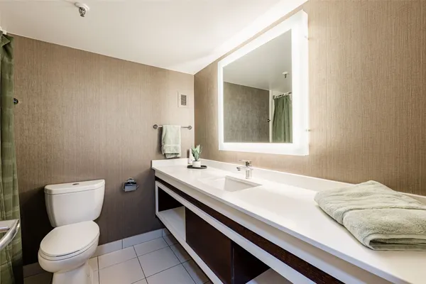 a bathroom with a granite countertop toilet sink and mirror