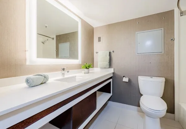 a bathroom with a granite countertop toilet sink and mirror