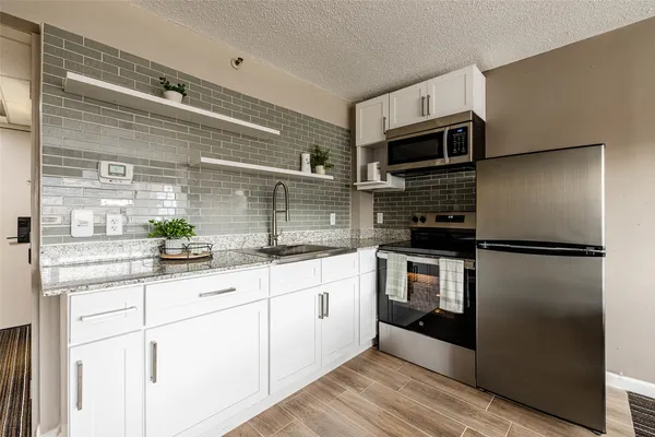 a kitchen with stainless steel appliances kitchen island granite countertop a refrigerator and a sink