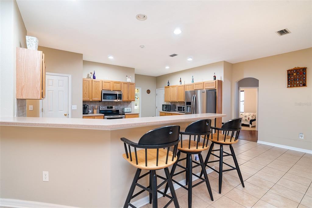 10903 Wildcat Drive Riverview, FL 33579 - Photo 6 of 45 a kitchen with stainless steel appliances kitchen island granite countertop a dining table chairs and a refrigerator