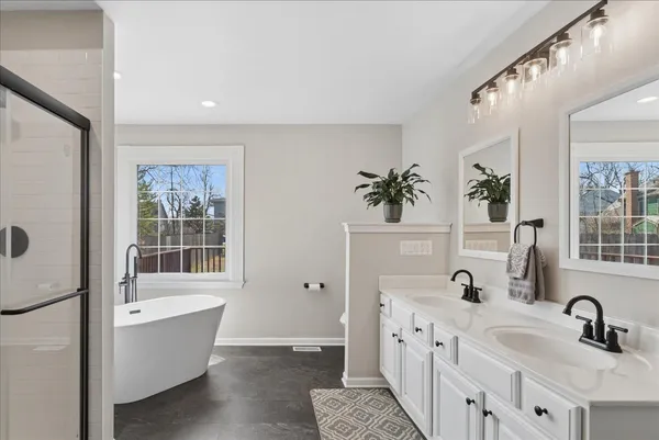a bathroom with a double vanity sink a mirror and a bathtub