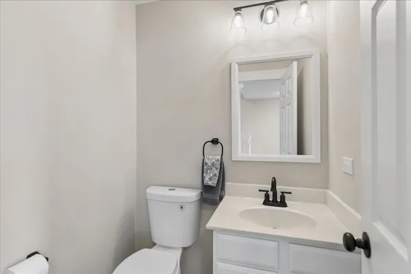 a bathroom with a toilet sink vanity and mirror