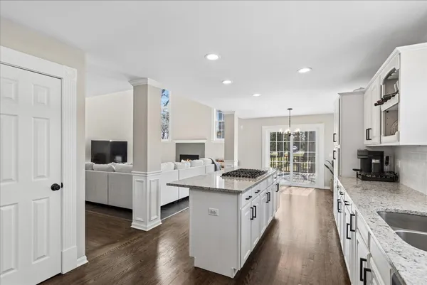 a large white kitchen with stainless steel appliances granite countertop a lot of counter space and wooden floor