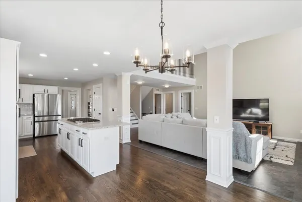 a living room with stainless steel appliances kitchen island granite countertop a stove and a wooden floors