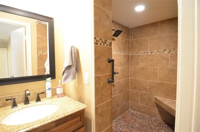 a bathroom with a granite countertop sink a mirror and a shower