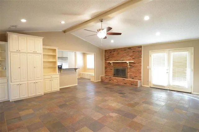a view of an empty room with a kitchen and window