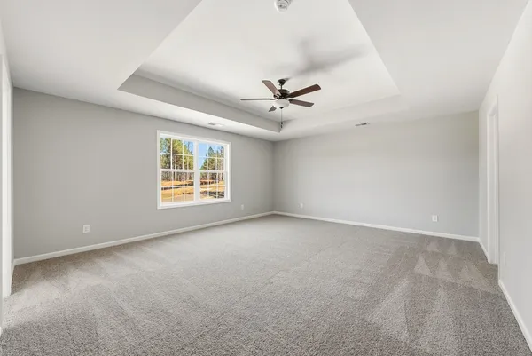 an empty room with windows and ceiling fan