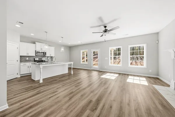 a living room with stainless steel appliances kitchen island hardwood floor and a large window