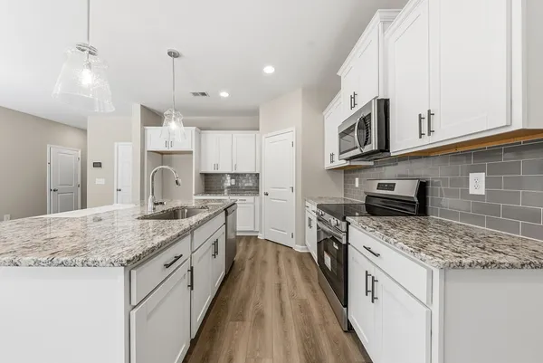 a large kitchen with stainless steel appliances granite countertop a stove oven and a white cabinets