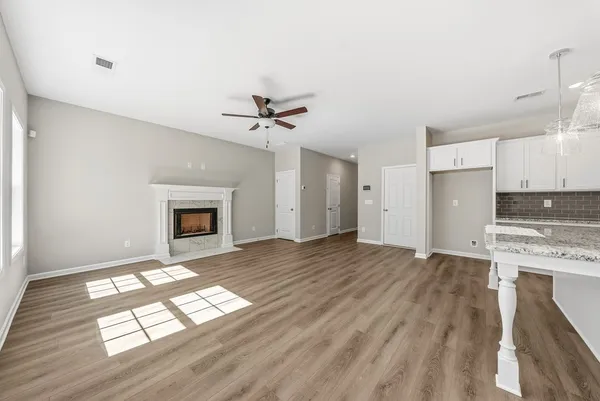 a view of empty room with kitchen and fireplace