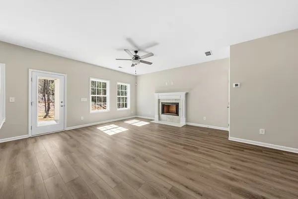 a view of an empty room with window and wooden floor