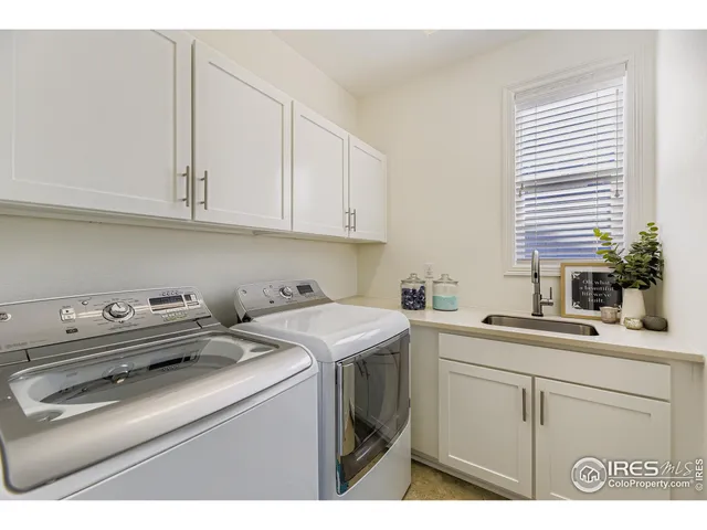 a utility room with stainless steel appliances white cabinets and a sink