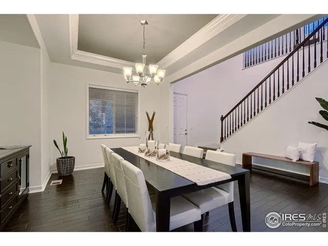 a dining room with wooden floor a chandelier a wooden table and chairs