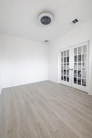 a view of an empty room with a window and wooden floor