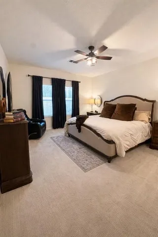 a spacious bedroom with a bed a ceiling fan and a dresser