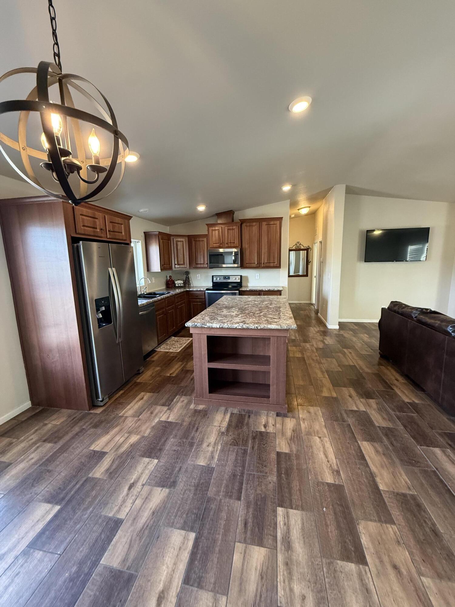a living room with stainless steel appliances furniture a fireplace and a flat screen tv