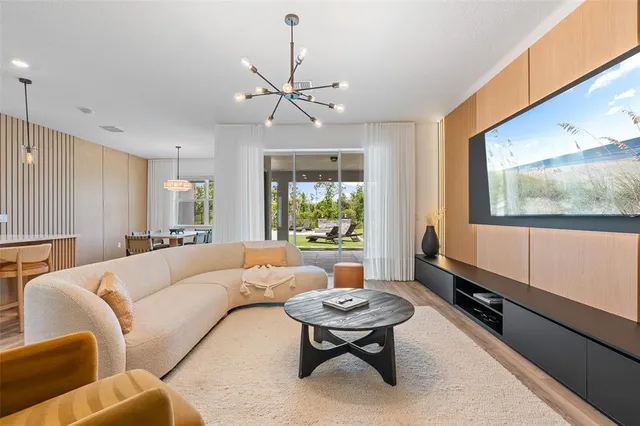 a living room with furniture kitchen view and a chandelier
