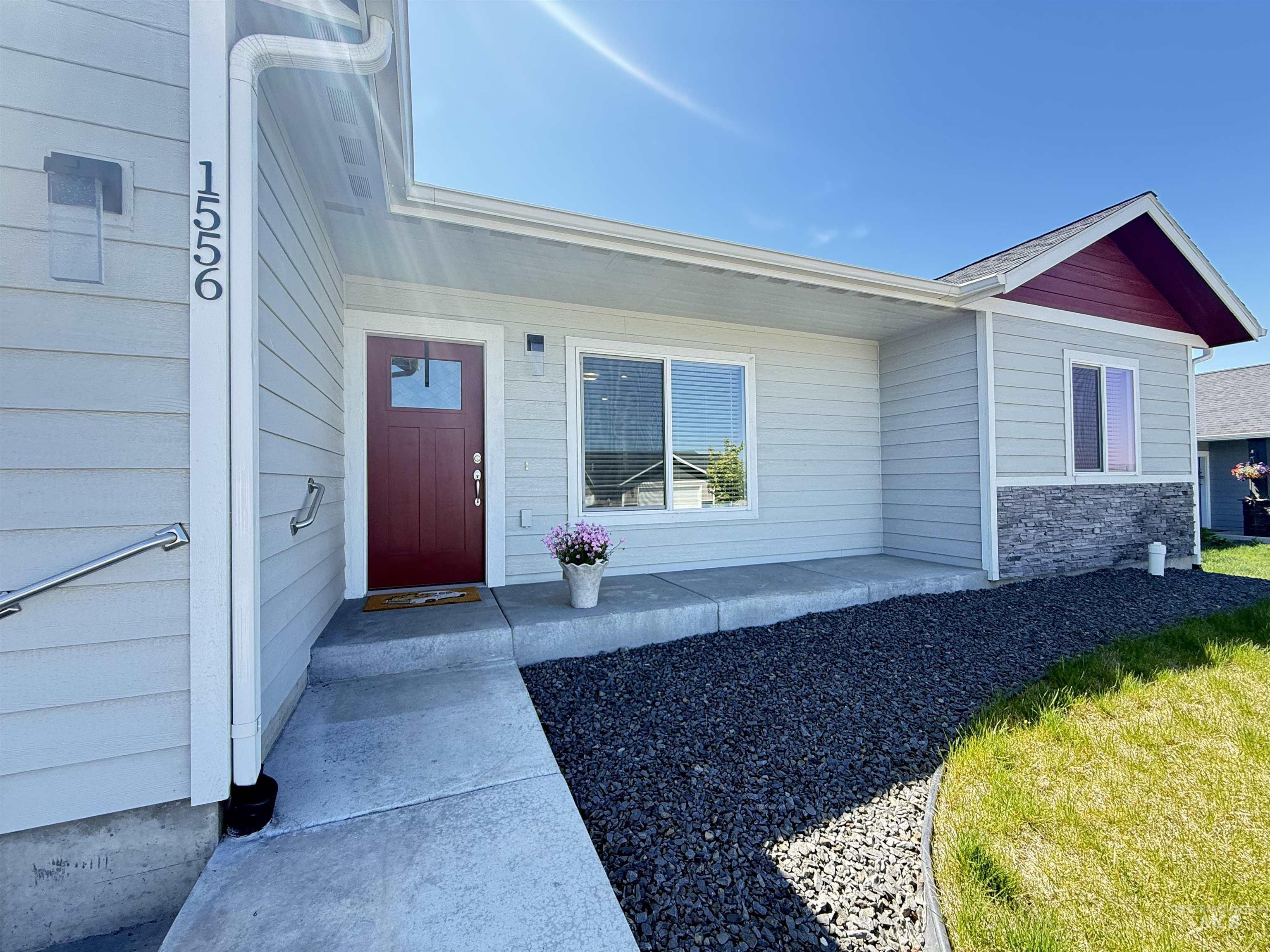 1556 Frontier Drive Lewiston, ID 83501 - Photo 2 of 23 Exterior featuring light grey horizontal siding, a red entry door with window pane, and a covered porch