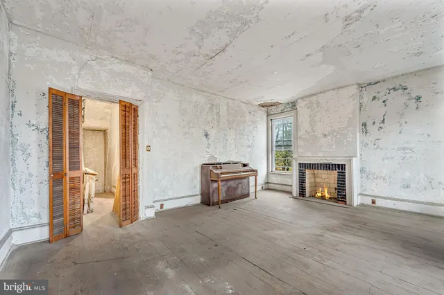 an empty room with fireplace and wooden floor