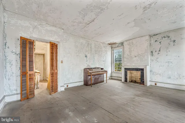an empty room with fireplace and wooden floor
