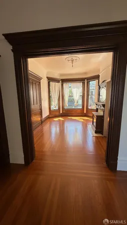 a view of an empty room with wooden floor and a window