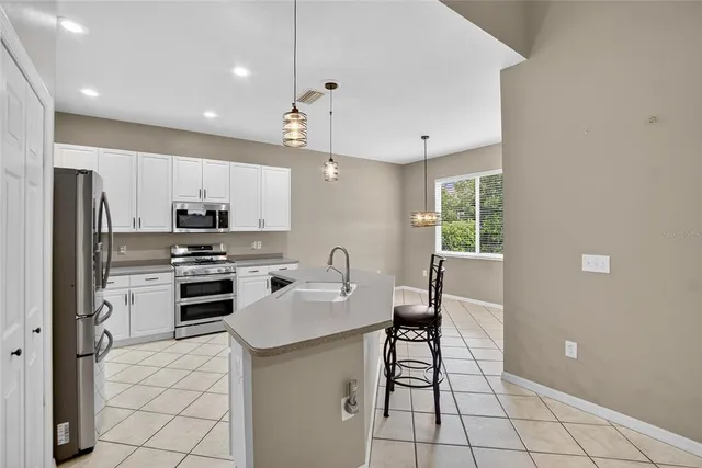 a kitchen with stainless steel appliances granite countertop a sink a stove a refrigerator and island with wooden floor