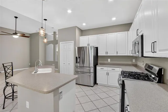 a kitchen with stainless steel appliances kitchen island granite countertop a sink a refrigerator and chairs