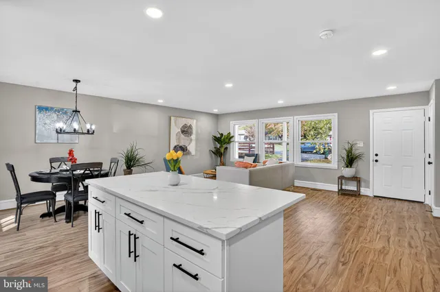 a living room with stainless steel appliances kitchen island a table and chairs in it