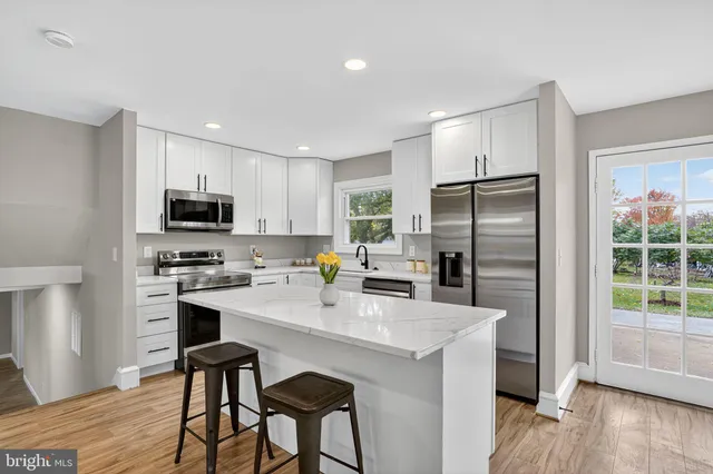 a kitchen with stainless steel appliances a microwave a sink a stove a refrigerator cabinets and wooden floor