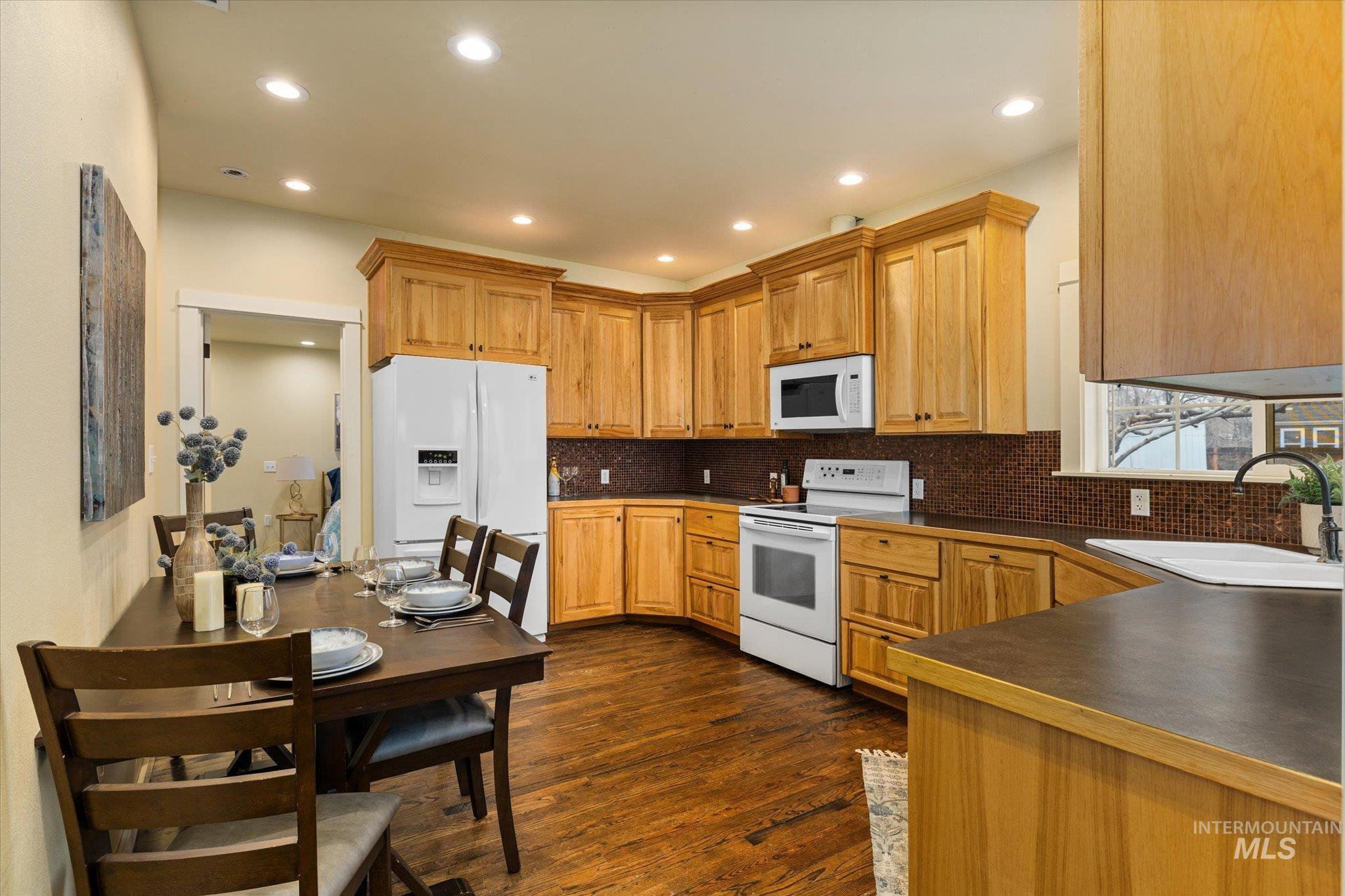 29410 Pearl Road Parma, ID 83660 - Photo 17 of 50 Kitchen featuring dark countertops, white appliances, dark wood-type flooring, tasteful backsplash, and recessed lighting