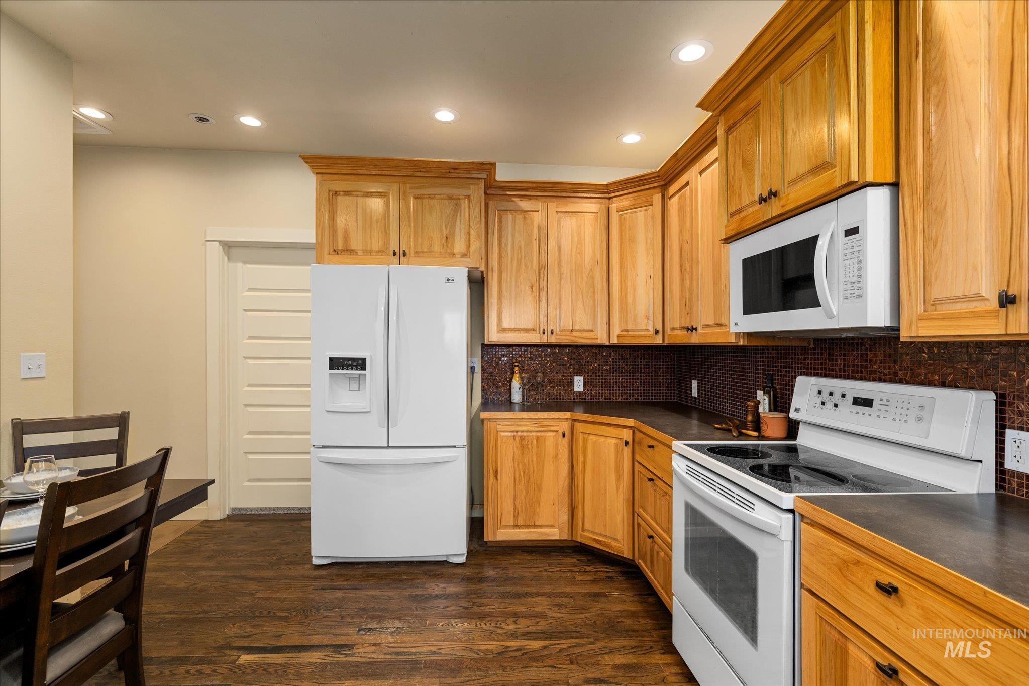 29410 Pearl Road Parma, ID 83660 - Photo 19 of 50 Kitchen with white appliances, dark wood-style flooring, dark countertops, recessed lighting, and tasteful backsplash