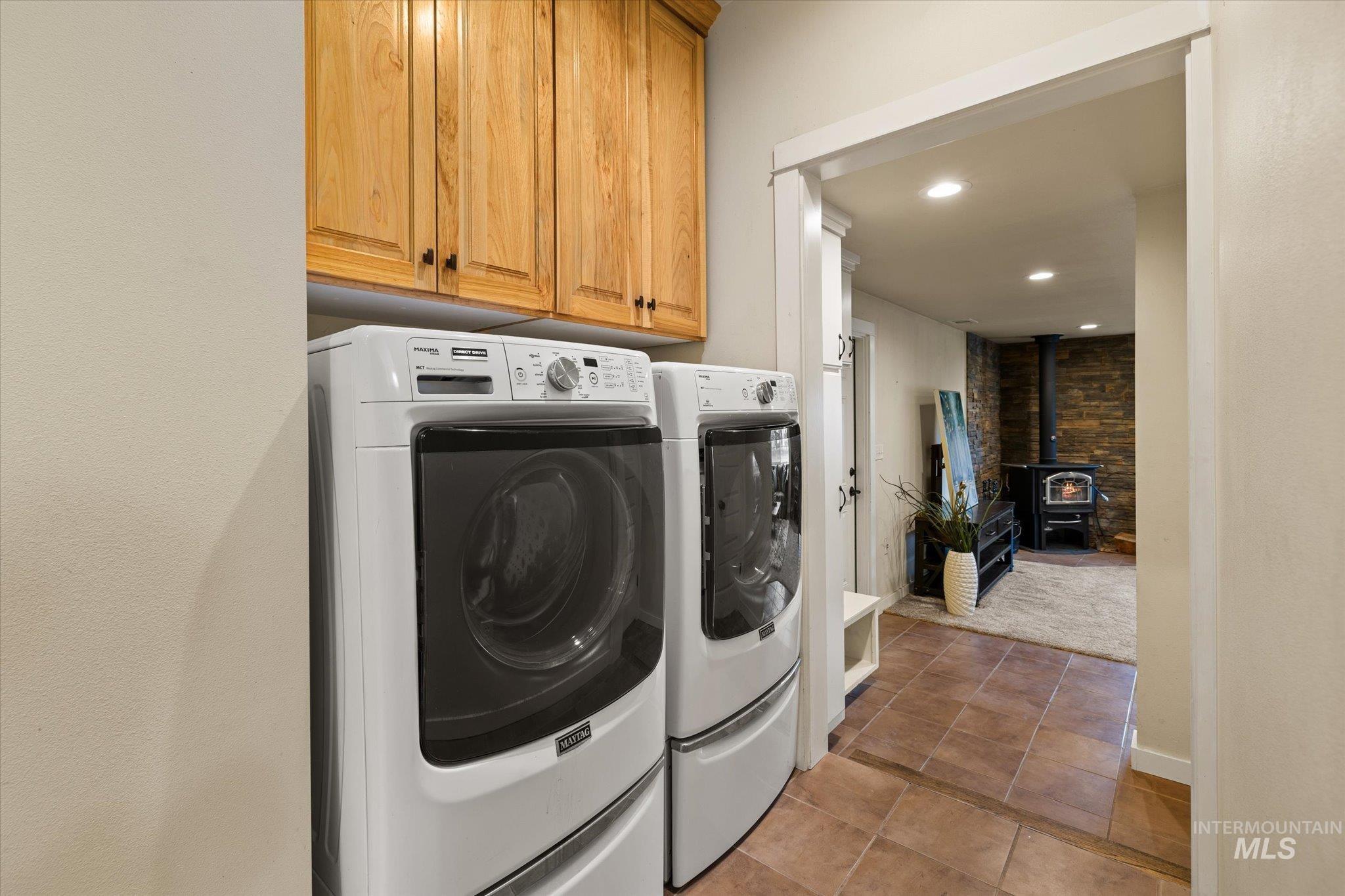 29410 Pearl Road Parma, ID 83660 - Photo 30 of 50 Laundry area with a wood stove, washer and clothes dryer, light tile patterned floors, cabinet space, and recessed lighting