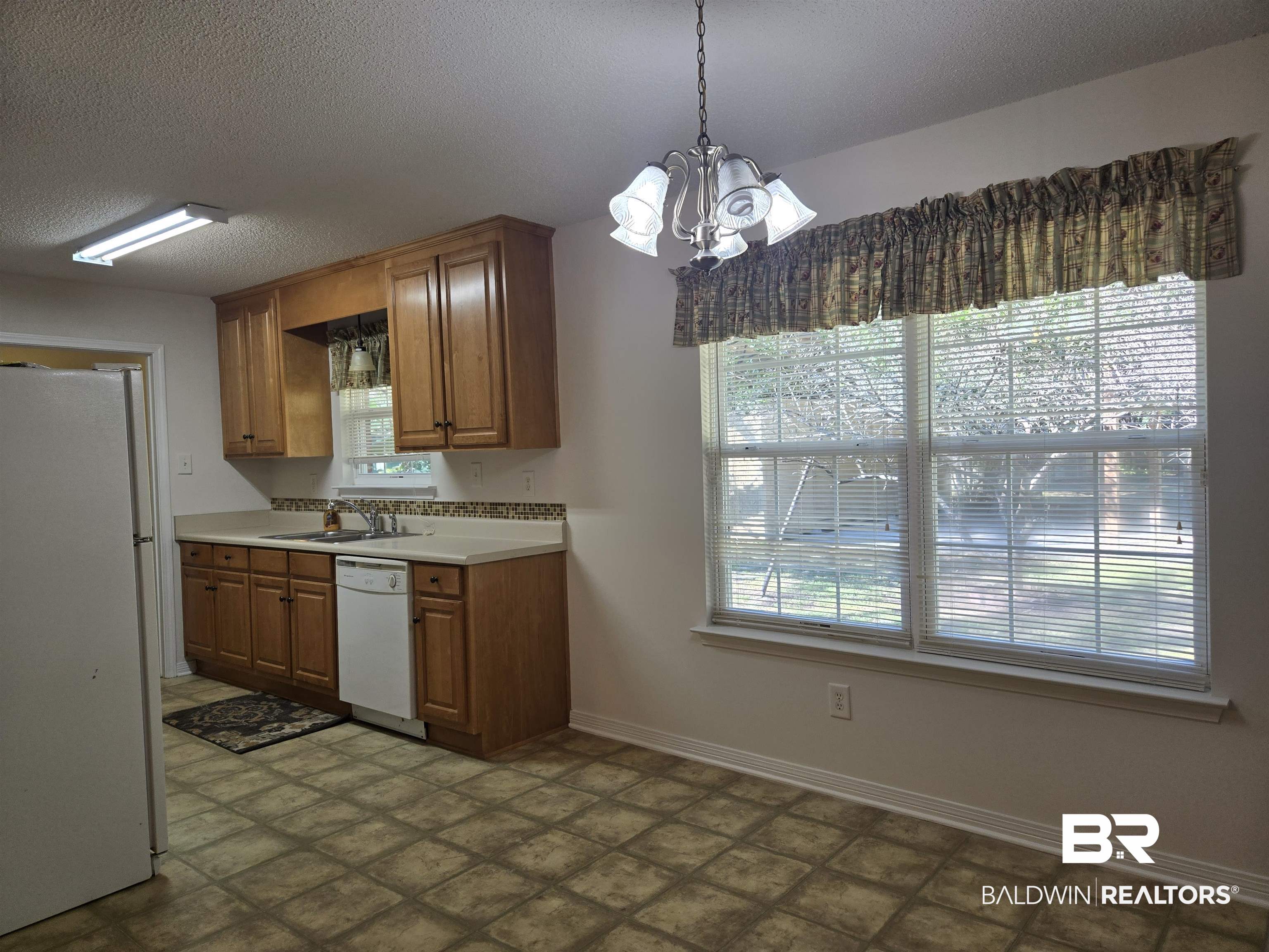 2554 Riverside Drive Mobile, AL 36605 - Photo 28 of 43 Kitchen featuring white appliances, light countertops, a textured ceiling, a chandelier, and pendant lighting