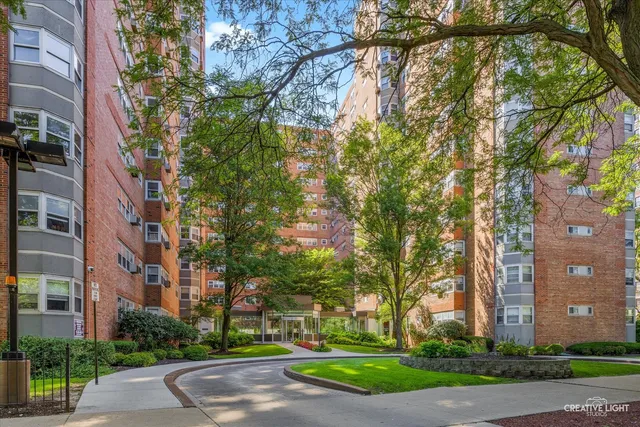 front view of a building with a yard and large trees